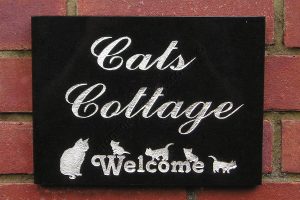 Cats Cottage house sign in Black granite, script font and welcome cats motif. Engraved and finished silver.